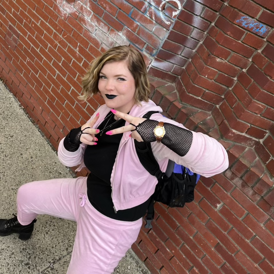 Magz1lla making the peace sign in front of brick wall with graffiti